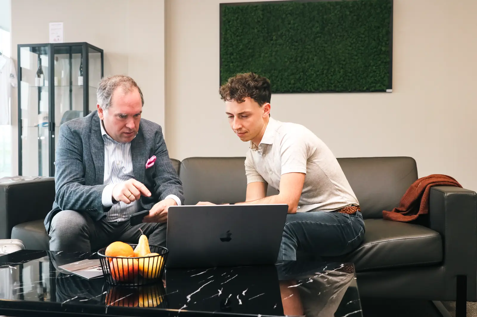 Thorsten Neumann und Christian Haselsberger in der Lounge am Laptop und mit Handy